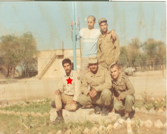 شخص نشسته از سمت چپ تصویر شهید محسن کلاهی